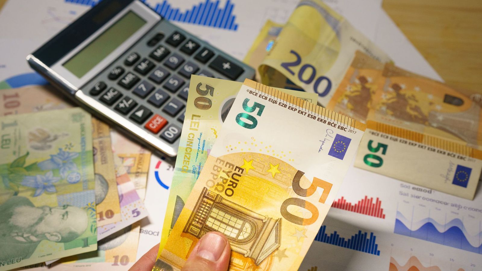 Une calculatrice et des billets posés sur un bureau